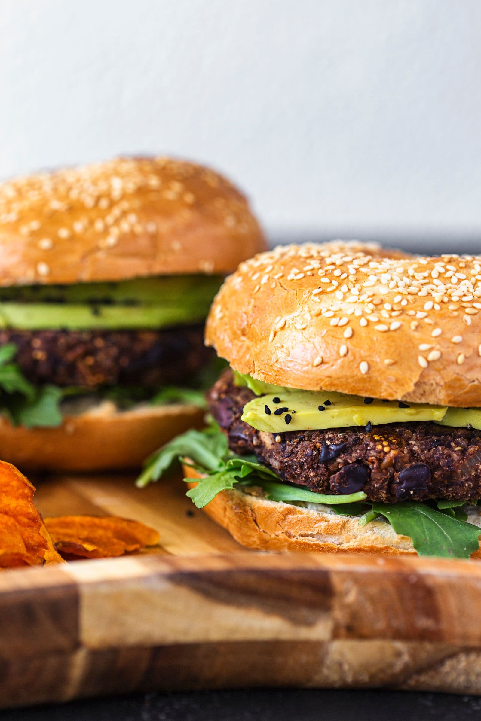 Close-up of juicy black bean burger in a bun with sweet potato fries.