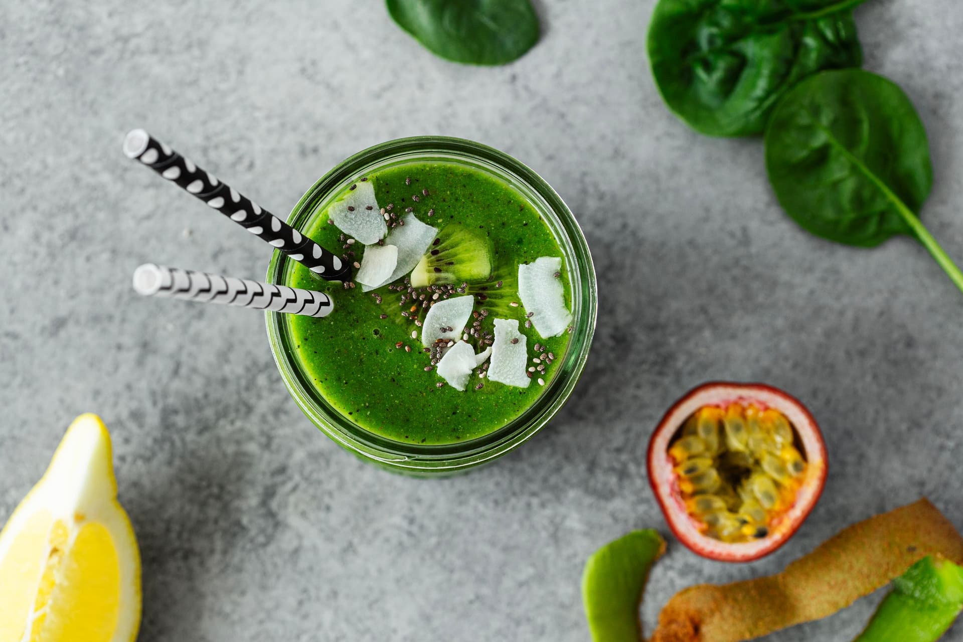 Green smoothie topped with chia seeds, coconut flakes, and kiwi, shot from above with fresh ingredients