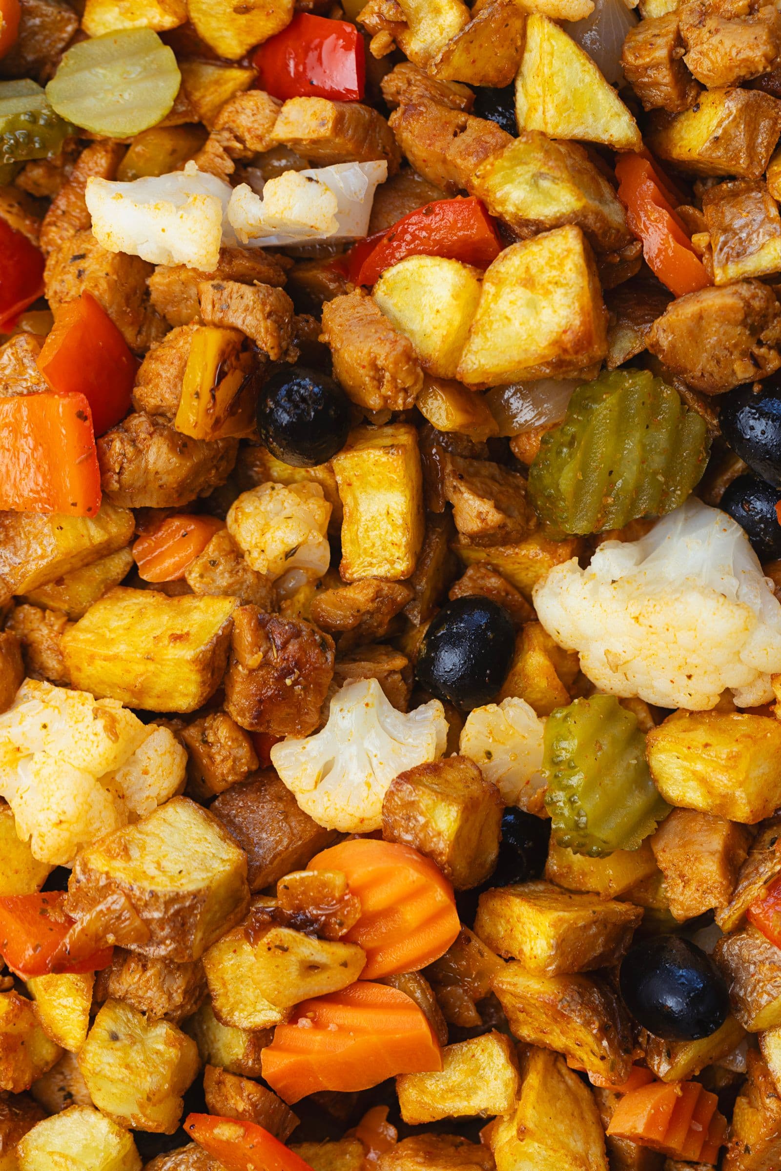 Close-up do pica pau de soja com batatas fritas, azeitonas, pickles de couve-flor e cenoura, nacos de soja caramelizados e pimentos