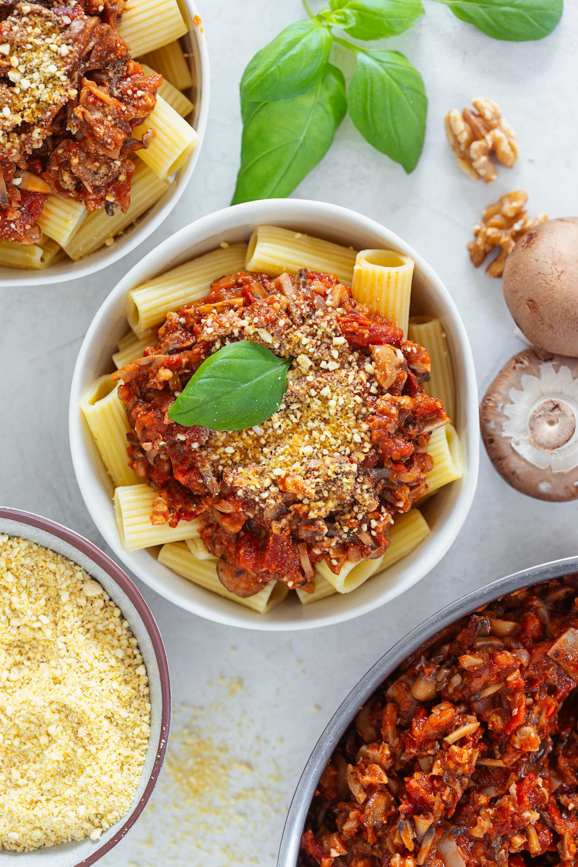 Bowl of rigatoni topped with spicy vegan mushroom and walnut bolognese and fresh basil.