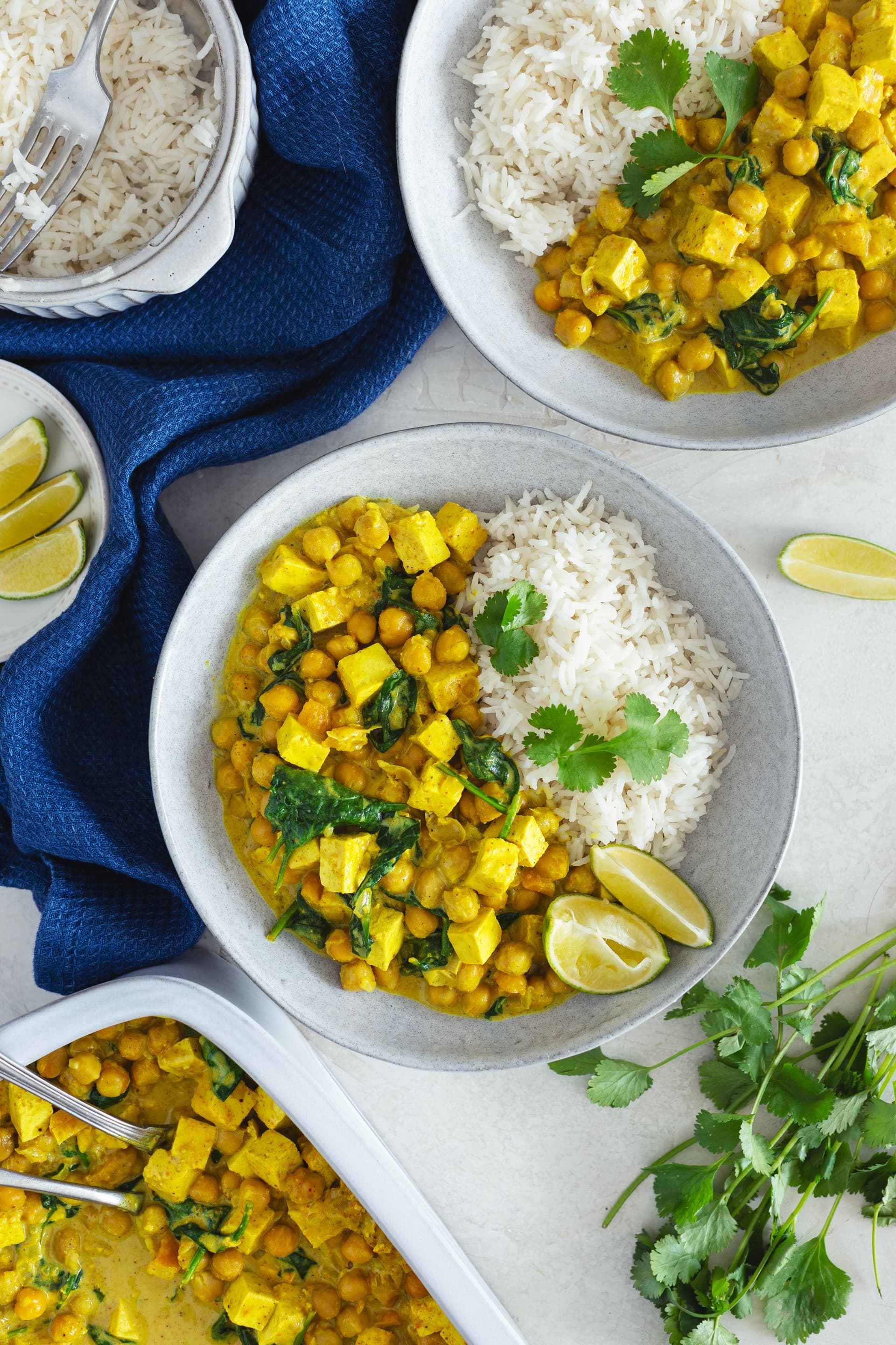Portion of chickpea tofu curry with rice served in a white bowl, garnished with coriander.