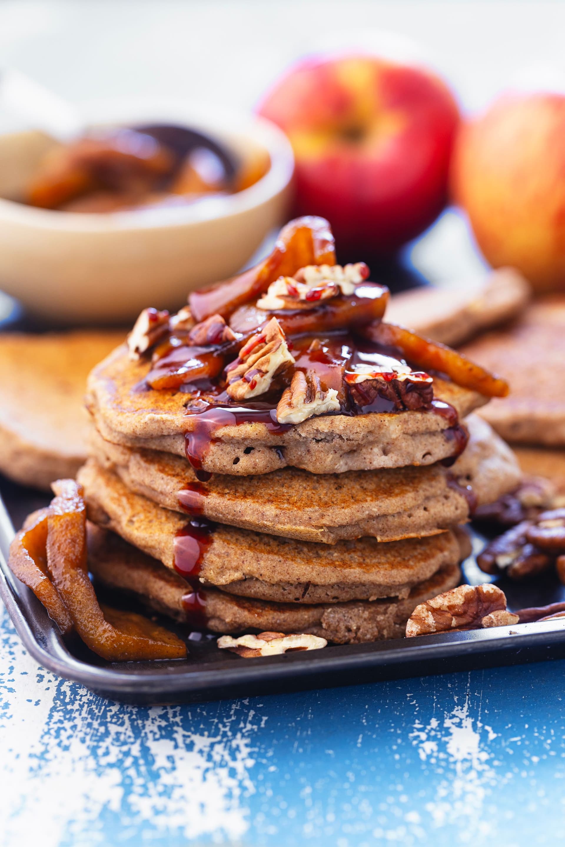 Close-up de panquecas fofas com maçã caramelizada com coco e fio de caramelo.