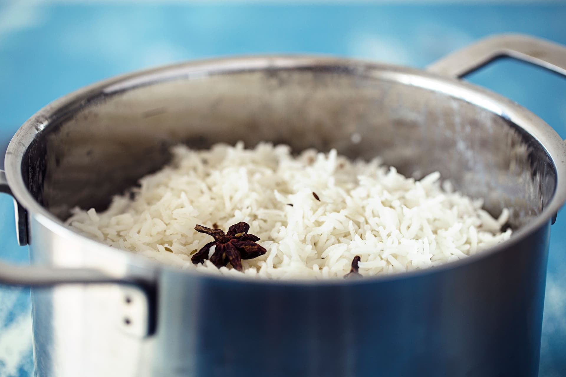 Panela com arroz basmati solto e fofo, acabado de cozinhar, com anis-estrelado por cima.