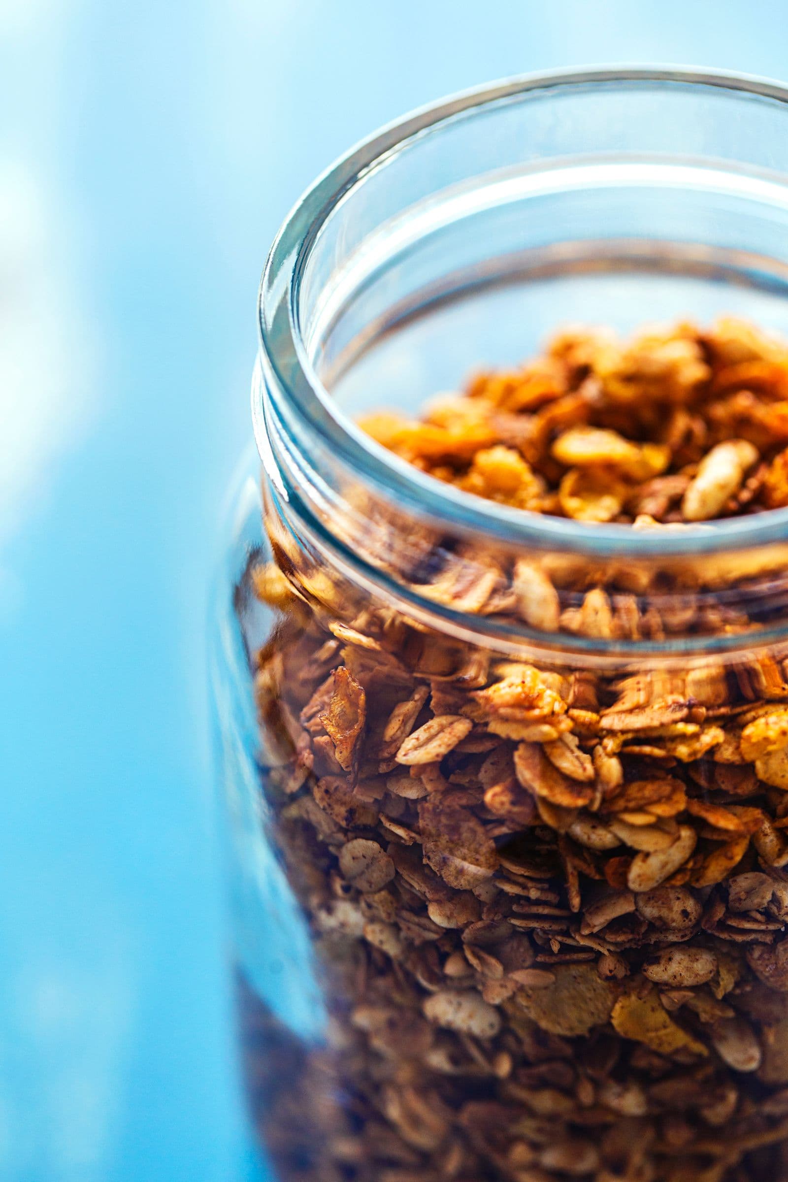 Close-up de granola dourada e crocante guardada num frasco de vidro.